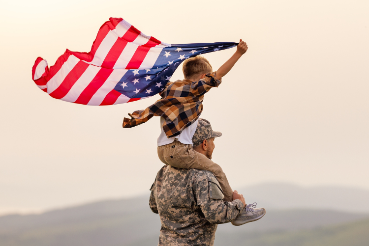 Soldier with child on shoulders holding an American flag