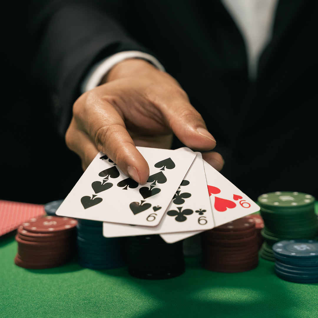 a hand holding cards over a poker table